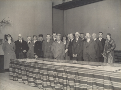 52 Groepsportret. De groep is opgesteld achter tafels [met tentoongestelde postzegels]. Vierde van rechts: O.E. Houtsma