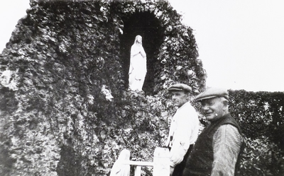 50-00078 In de tuin van het Grote Gesticht voor de grot van Lourdes met het Heilg Hart beel, staat Jan te Plate, de man ...