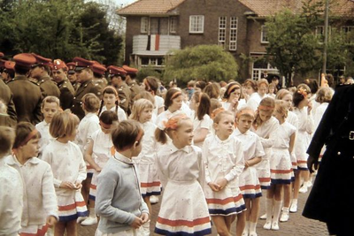 0577 Meisjes in witte bloes en rok met een rood-wit-blauwe banen. Achter hen Engelse militairen die in Münster in ...