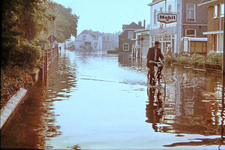 0966 Wateroverlast. Een fietser baant zich een weg door het water