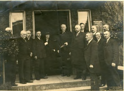 1095-44-006 Groepsfoto voor de ingang van het gemeentehuis. In de deuropening staat burgemeester Van Dorth tot Medler ...