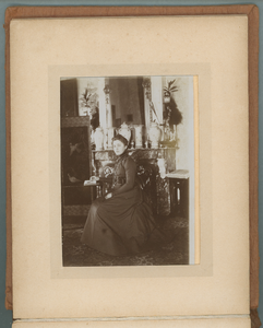 283-0005 Vrouw zittend bij leestafel, waarop een opengeslagen fotoalbum ligt, 1901-1910