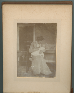 283-0019 Een jonge vrouw zit met een baby in haar armen, 1902-1905