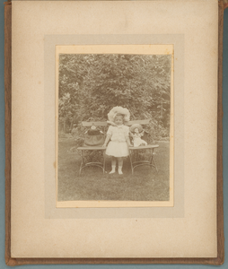 283-0020 Een jong meisje toont twee van haar poppen in de tuin, 1905-1910