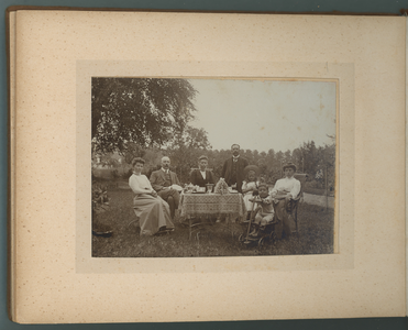 283-0021 Mensen zitten aan een tafel in een tuin, 1905-1910
