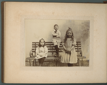 283-0023 Twee meisjes en een jongen bij een bankje, 1905-1910