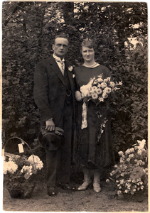 415 Kabinet-portret van een onbekend echtpaar, gefotografeerd in de tuin. De bruid houdt een groot bloemstuk vast en de ...