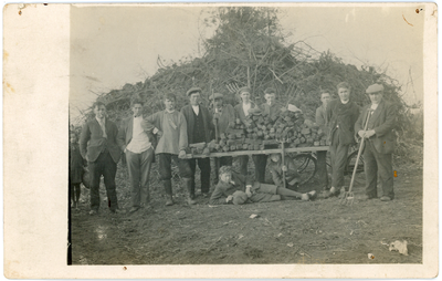 416 Groepsportret van jonge mannen bij een paasbult. De heren houden een houten ladder vast, waarop een stapel turven ...