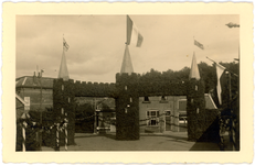 442 Koninginnedag in Borne. Een versierde boog, met wapperende vlaggen, ter hoogte van de driesprong ...