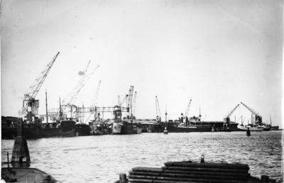 2223 Delfzijl (haven) : Kade met kranen en afgemeerde schepen, vanuit de haven gezien, 1937-12