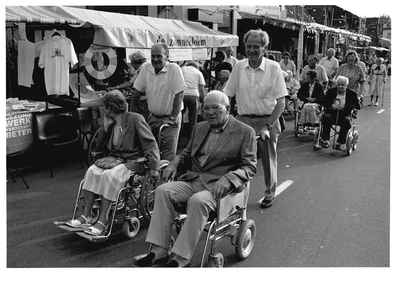 GAV-F-W-0943 Vrijwilligers van de Zonnebloem rijden mensen in rolstoel rond over de klompenmarkt.