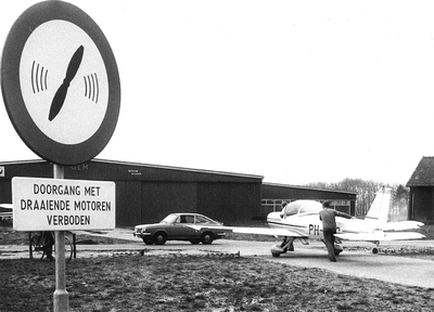 GAV-F-W-1980 Verkeersbord op vliegveld Teuge aan De Zanden in Teuge.De man duwt het vliegtuig naar de hangar toe.