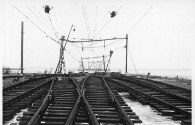 156845 Afbeelding van de overstroomde en deels weggespoelde emplacement bij Lage Zwaluwe, na de watersnoodramp.