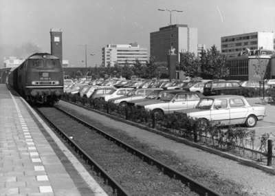 154561 Gezicht op de P+R-parkeerplaats van het N.S.-station Nijmegen te Nijmegen met links diesellocomotief 215 026-6 ...