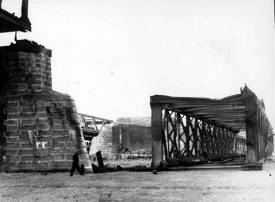 157339 Gezicht op het met explosieven neergehaalde brugdeel van de tijdens de oorlog vernielde spoorbrug over de Waal ...