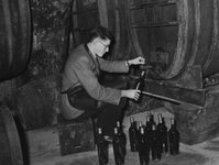 57723 Afbeelding van het vullen van wijn in flesjes uit een groot vat in de kelder van de wijnhandel H. Bloem ...