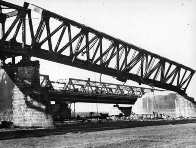 157336 Gezicht op een scheefhangend brugdeel van de tijdens de oorlog vernielde spoorbrug over de Waal bij Zaltbommel. ...