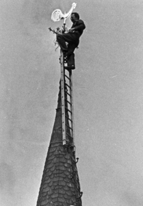 88753 Afbeelding van schilder Luuk Hoogstraten tijdens het plaatsen van de gerestaureerde haan op de toren van de Kapel ...