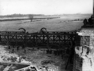 157340 Gezicht op het met explosieven neergehaalde brugdeel van de tijdens de oorlog vernielde spoorbrug over de Waal ...