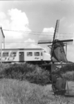 151021 Gezicht op een molen en een passerend electrisch treinstel mat. 1964 (plan V) van de N.S. ter hoogte van Hazerswoude.