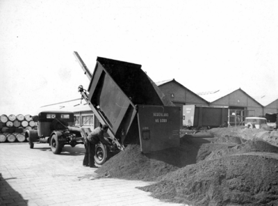 163596 Afbeelding van een vrachtauto tijdens het lossen van een kolenlaadkist van de N.S. met steenkool.