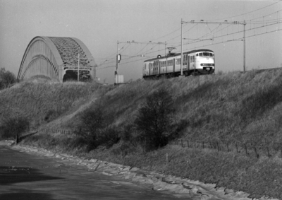 153672 Gezicht op de spoordijk bij Culemborg met een electrisch treinstel plan V (mat. 1964) van de N.S. en op de ...