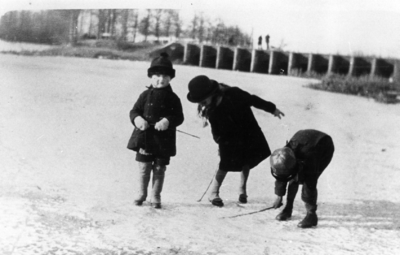 77482 Afbeelding van de kinderen uit het gezin Swierstra op het ijs voor de Brug met de 12 Gaten in de Weg naar ...
