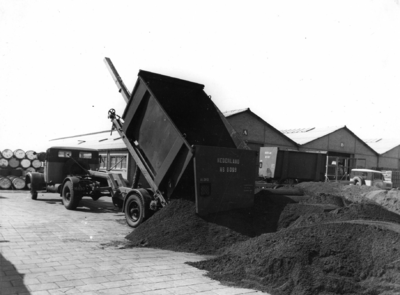 163590 Afbeelding van een vrachtauto tijdens het lossen van een kolenlaadkist van de N.S. met steenkool.