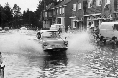 92332 Afbeelding van de wateroverlast aan de zuidzijde van de Hessenweg te De Bilt; met een auto rijdend door het water.