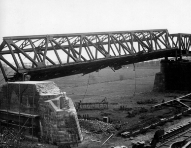 157335 Gezicht op een scheefhangend brugdeel van de tijdens de oorlog vernielde spoorbrug over de Waal bij Zaltbommel.
