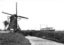 151336 Gezicht op een molen in een polderlandschap met op de achtergrond een electrisch treinstel plan V (mat. 1964) ...