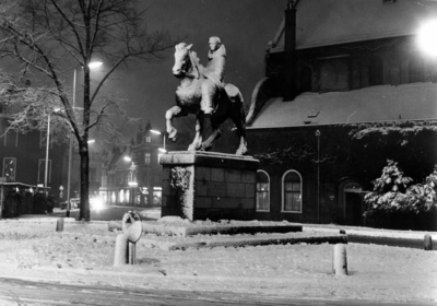 128161 Gezicht op het besneeuwde beeld van Sint Willibrord op het Janskerkhof te Utrecht, bij avond.