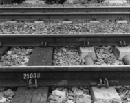 166474 Detail van een spoorlijn met een overgang van houten naar betonnen dwarsliggers.