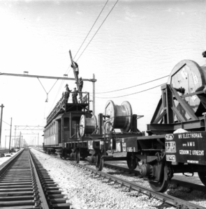 166485 Afbeelding van een werktrein van de N.S. bestaande uit een montagewagen en haspelwagens, tijdens het aanbrengen ...