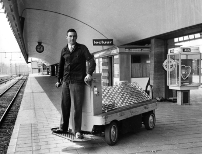 167841 Afbeelding van een stationsassistent van de N.S. met een elektrokar voor bagagevervoer op het perron van het ...