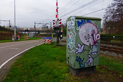 827706 Afbeelding van graffiti op een relaiskast bij de spoorwegovergang in de Voordorpsedijk te Utrecht.