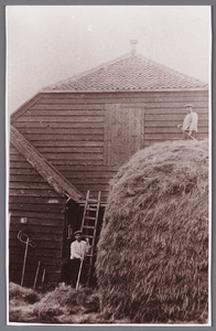 WAT002001505 George Johannes de Vries rechts boven op de hooiberg van boerderij naast gemeentehuis, met helper buurman ...