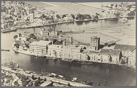 WAT002002349 Luchtaanzicht op de fabriekswand aan de Zaan met vlnr:Rouen (lichtgrijze vierkante gebouw), Pakhuis Indië, ...