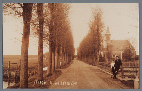 WAT002003013 Aanzicht op het Oosteinde met rechtsachter de Ned. Herv. Kerk en twee (onbekende) jongemannen die poseren ...