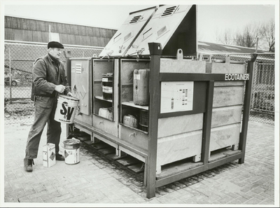 NNC-86-282-01 De beheerder van het inzamelstation voor huisvuil staat bij het depot voor klein chemisch afval dat ...