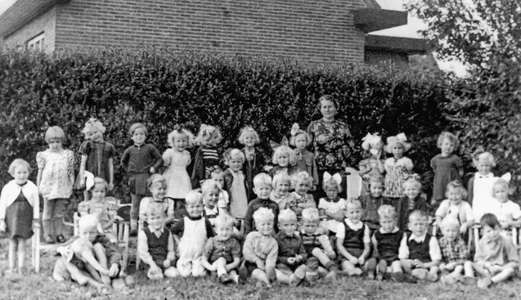 OVI-00002321 groepsfoto kleuterschool met hoofdleidster M.Forrer in de tuin achter de RK lagere school