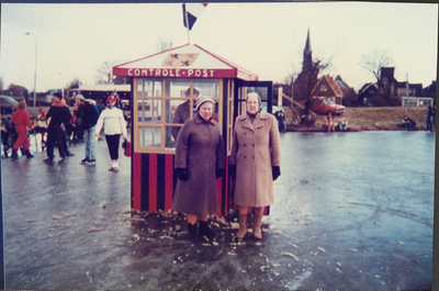 OVI-00000176 Mevrouw Mobron en mevrouw Blom (vlnr) bij de stempelpost aan het begin van het Ilperveld in de winter van 1987