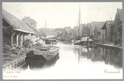WAT001012421 Links de Houtloods van de familie Brantjes aan de Achterdijk, met rechts een Tjalk