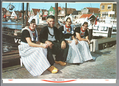 WAT001013293 Ansichtkaart van drie Volendamse dames en een oude Volendamse man. Ze zitten samen in de haven.