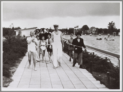 WAT001017215 Foto: Een bonte uitmonstering paraderen mensen in 1958 door het zwembad tijdens het gekostumeerd ...