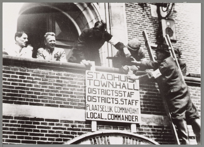 WAT001017523 Mensen van het verzet hangen een bord op aan de voorgevel van het stadhuis.Tekst: Stadhuis, Town Hall, ...