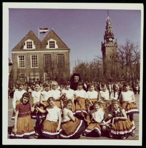 WAT050000889 Koninginnedag 1962. Een groep meisjes in oranje rokken achter het oude Stadhuis