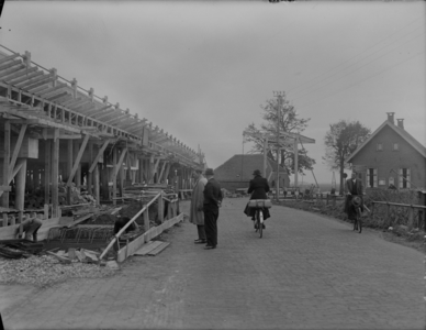 100 Staphorst: Opname van fietsers en toeschouwers bij wegwerkzaamheden aan de verkeersweg, met een brug op de ...