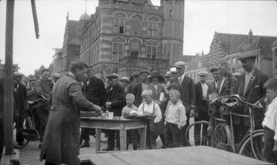283 Brink, voor de Waag. Standwerker houdt verkooppraatje voor aandachtig publiek., 10-04-1945 - 30-04-1945
