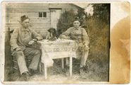 1-0008 Twee militairen aan een tafel met daarop een hond, 1920
